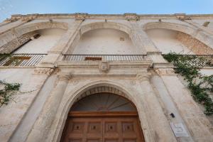 un edificio con due archi e una porta di legno di Il Quinto Elemento - Residence Of Charme a Ostuni