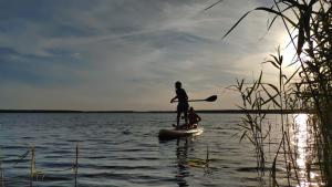 a man is standing on a paddle board in the water at Bernstein Apartments in Pouch