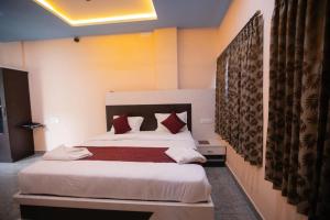a bedroom with a bed with white sheets and red pillows at Hotel Mysuru Haven in Mysore