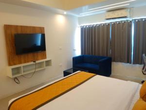 a bedroom with a bed and a chair and a television at Hotel Mysuru Haven in Mysore +20 photos