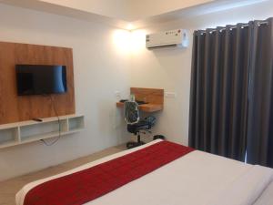 a bedroom with a bed and a tv and a chair at Hotel Mysuru Haven in Mysore