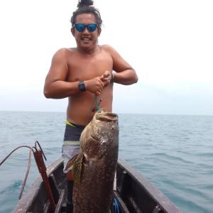 a man holding a large fish in a boat at Mapaddegat Surf House in Simpatdegat