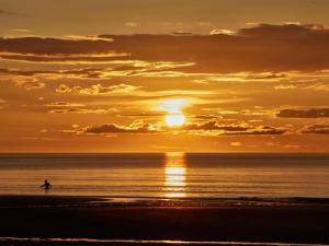 a surfer in the ocean at sunset at Le Grand Hotel de Cabourg - MGallery Collection in Cabourg