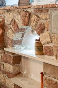 a stone wall with two shelves with wine glasses at The Stone Nest in Koroni