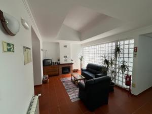 a living room with a black couch and a tv at Retiro da Devesa in Pedrógão Grande