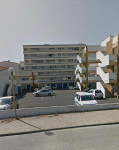a parking lot with cars parked in front of a building at Les sables d'or, vue mer, wifi et parking privé in Saint-Hilaire-de-Riez