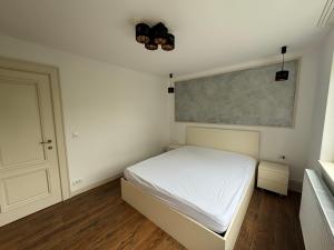 a small bedroom with a white bed and a chalkboard at City Urban Apartament in Baia Mare