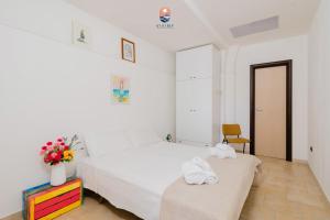 a white bedroom with a bed and a chair at Dimora Cavour by vivimy in Tuglie