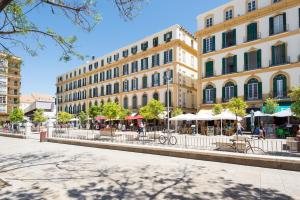 un edificio en una ciudad con mesas y sombrillas en Plaza Picasso, en Málaga