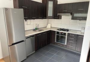 a kitchen with wooden cabinets and a stainless steel refrigerator at Apartament Lipowa in Kalisz