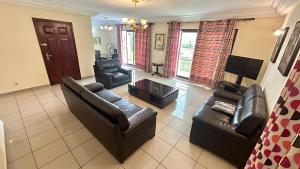 a living room with two leather couches and a tv at Résidence saint James in Douala