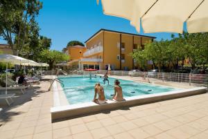 two women sitting on a bench next to a swimming pool at Essenza Residence in Cervia
