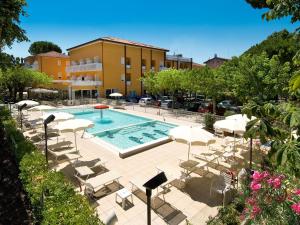 a swimming pool with white chairs and a building at Essenza Residence in Cervia