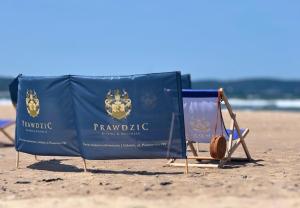 a sign on the beach with a chair and a towel at Prawdzic Family Resort & Wellness in Gdańsk