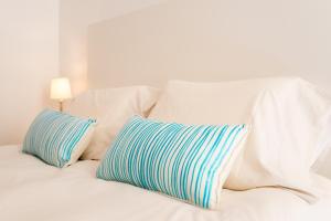 a white bed with two blue and white pillows at Plaza Picasso in Málaga