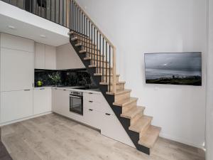 a staircase in a kitchen with white walls and wooden floors at Brand New Loft 61 in Pakopi