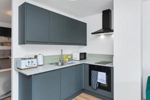 Una cocina con gabinetes azules y un fregadero. en Matlock Town Centre Flat Near Transport Links, en Matlock