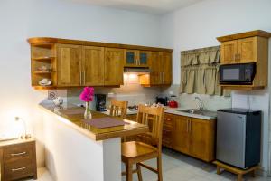 a kitchen with wooden cabinets and a table and a refrigerator at Bugambilias Suites in Loreto