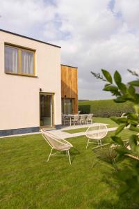 ein Haus mit zwei Stühlen und Tischen auf dem Rasen in der Unterkunft ElloStays in Middelkerke + 29 Fotos