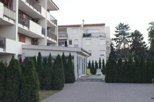 a building with a bunch of trees in front of it at Honey Wellness Apartman in Siófok