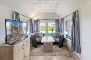 Una sala de estar de RV con TV y sillas. en Haus Seeblick _ Wohnung 2, en Dagebüll