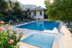 a swimming pool with chairs and a house at Green Garden Otel in Kemer