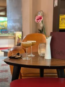 a table with two glasses and a flower in a vase at Hotel Les Vallées Labellemontagne in La Bresse