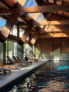 a swimming pool with benches and a wooden ceiling at Hotel Les Vallées Labellemontagne in La Bresse