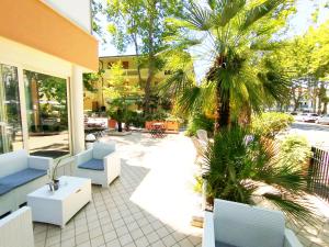 a patio with chairs and a palm tree next to a building at Hotel Milord in Cesenatico