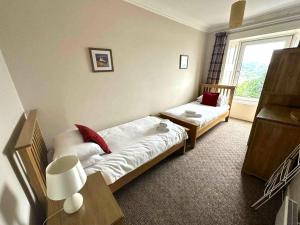 Un dormitorio con dos camas y una ventana. en McCaig's Tower Apartment, en Oban