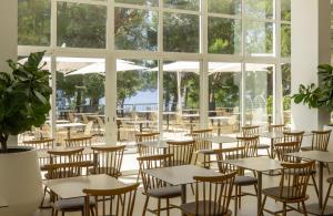 a restaurant with tables and chairs and windows at Bluesun Hotel Borak in Bol