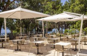 an outdoor patio with tables and chairs and umbrellas at Bluesun Hotel Borak in Bol