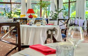 a dining room with tables and chairs with wine glasses at Hôtel Les Vallées Labellemontagne in La Bresse