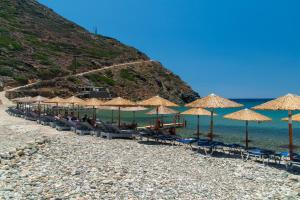 a beach with many straw umbrellas and the ocean at Green Bay Studio 1 in Sifnos