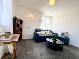 ミルトン・キーンズにあるModern 5 Bedroom House with Parking in Central Milton Keynesの青いソファとテーブルのあるリビングルーム