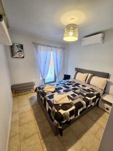 a bedroom with a black and white bed and a window at Daisy House Golden Beach Area in Potamia