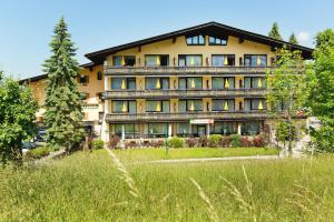 a large building with a grass field in front of it at Hotel Berghof Graml in Hallwang