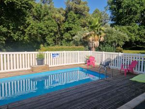 a pool with two chairs and a table and a fence at Le Nid Cabailla in Coimères