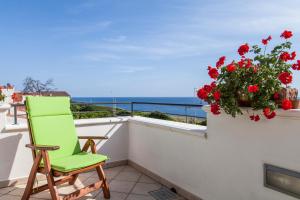 a green chair on a balcony with red flowers at Salento Mare Daniela in Leuca