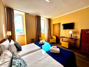 a hotel room with a large bed and a television at Greif Hotel Maria Theresia in Trieste