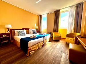 a hotel room with a bed and a chair at Greif Hotel Maria Theresia in Trieste