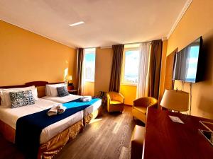 a hotel room with two beds and a flat screen tv at Greif Hotel Maria Theresia in Trieste