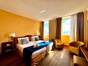 a hotel room with a bed and a chair at Greif Hotel Maria Theresia in Trieste