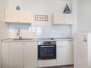 ニヴィーチェにあるApartment Martina by Interhomeの白いキャビネット、シンク、オーブン付きのキッチンが備わります。