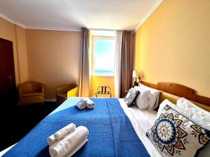 a bedroom with a blue bed with towels on it at Greif Hotel Maria Theresia in Trieste