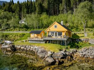 a yellow house on a hill next to a river at Holiday Home Eseviki by Interhome in Balestrand