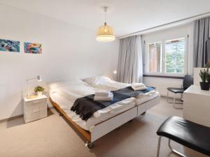 ダボスにあるApartment Allod Park Haus B 202 by Interhomeのベッドと机のある白い寝室