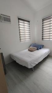 a bed in a white room with two windows at 3-Bedroom House in NorthPoint in Talisay