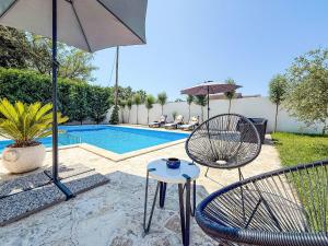 a patio with two chairs and an umbrella and a pool at Holiday Home Tina & Tino by Interhome in Briševo