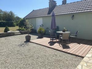 eine Terrasse mit Tisch und Sonnenschirm in der Unterkunft Holiday Home Cottage du Hamel es Clos by Interhome in Bretteville-sur-Ay